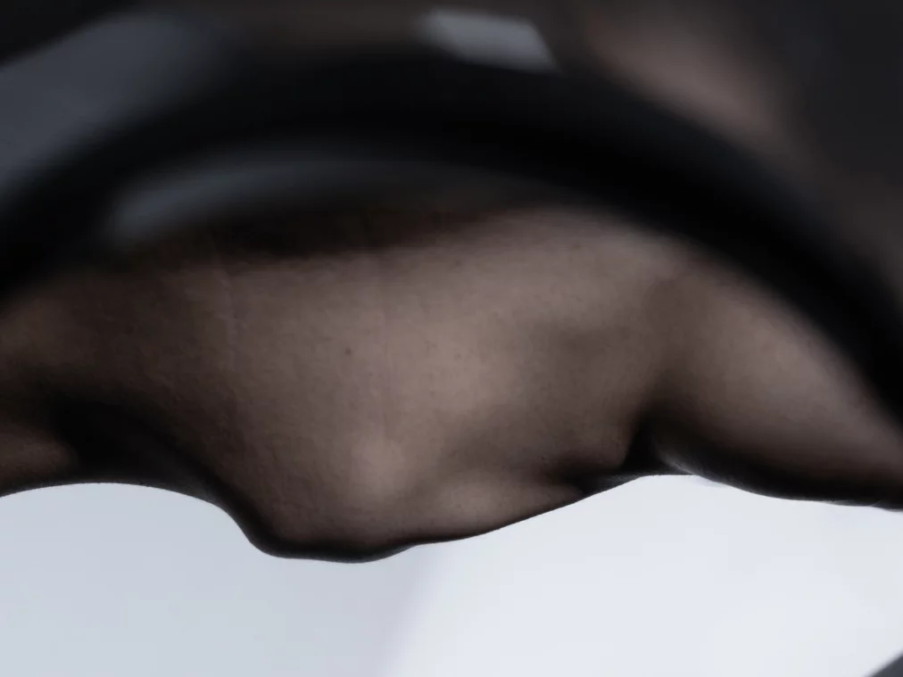 Abstrakte Nahaufnahme einer dunklen, dünnen Membran oder Oberfläche, die sich wellenförmig spannt und im Gegenlicht eine weiche, organische Struktur erkennen lässt.